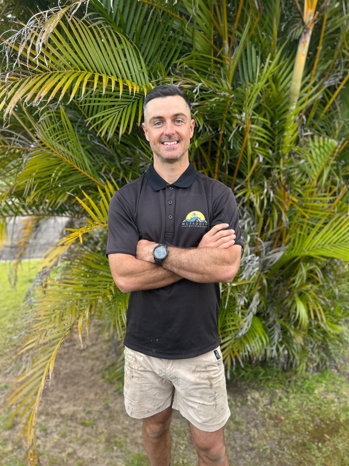 Tom McFadden, builder and owner of McFadden Building, arms crossed in a branded black work polo outdoors in the Northern Rivers NSW