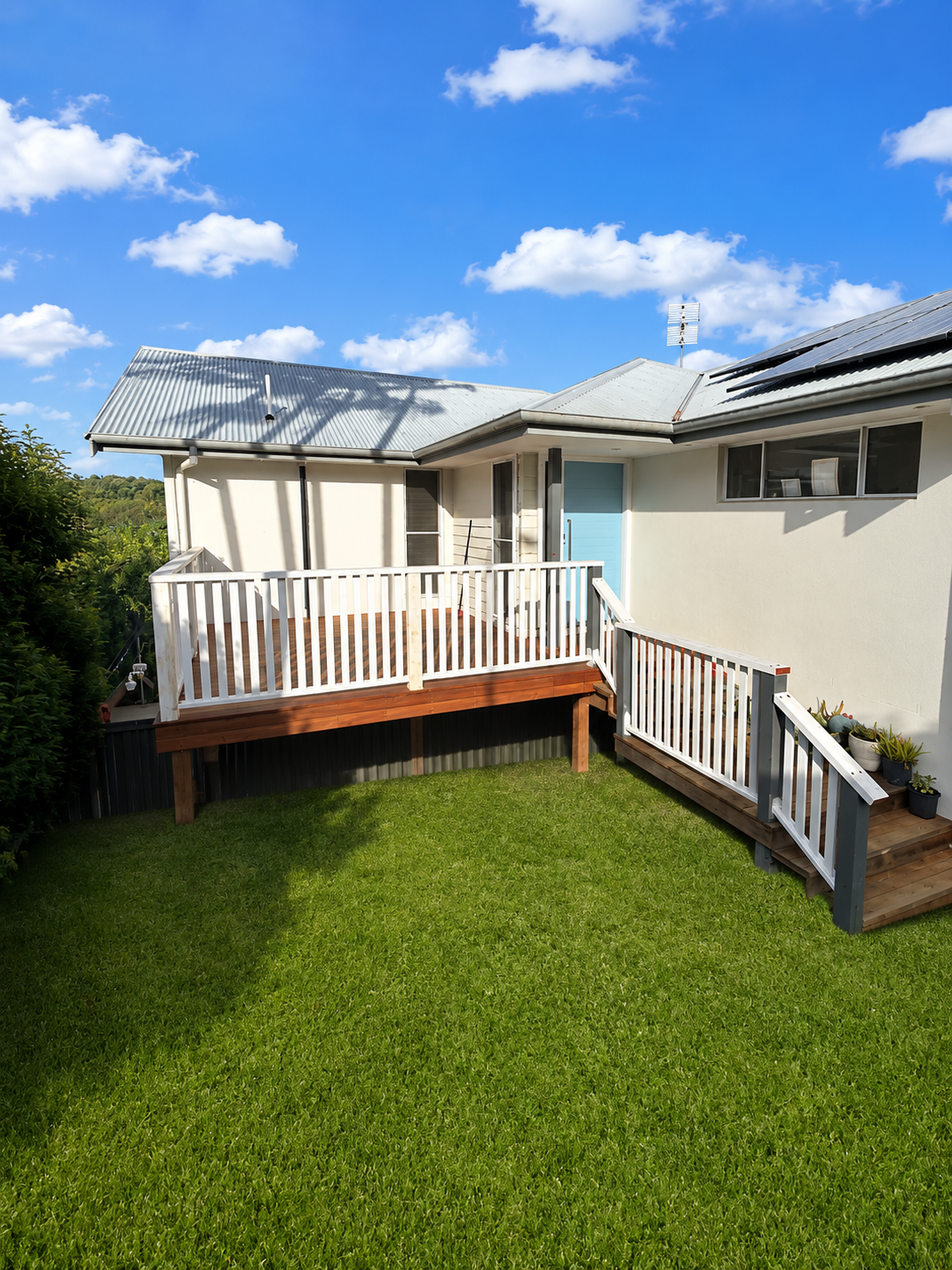 Elevated hardwood deck with white picket railing stepping down to a lawn, built in the Northern Rivers