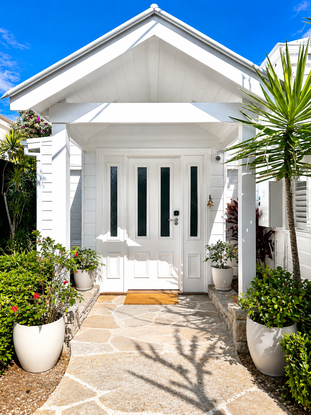Byron Bay home entry built by McFadden Building — gabled portico, white pillars and flagstone walkway framed by palms